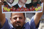 Demonštrant s fotografiou Mahmúda Ahmadinedžáda, Bašara al-Assada a Hassana Nasralláha. Zdroj: www.britannica.com
